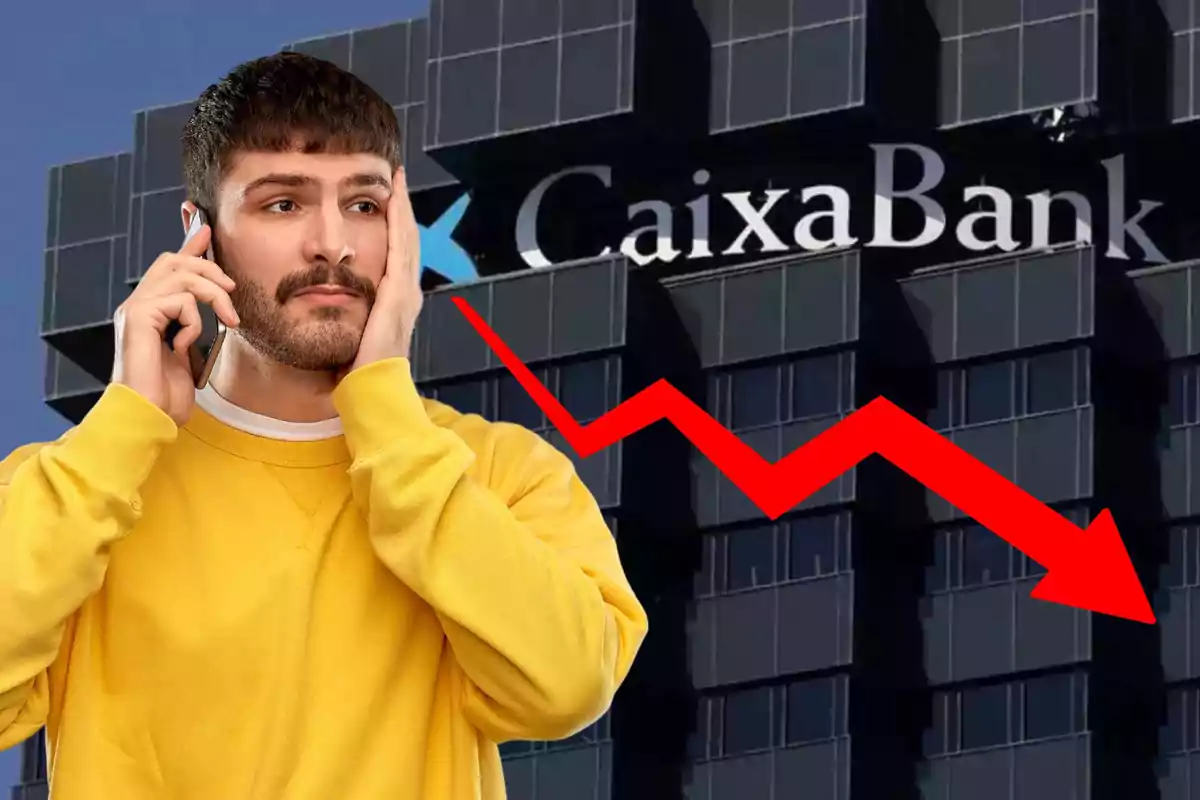 Un hombre con suéter amarillo hablando por teléfono y con expresión preocupada, con un edificio de CaixaBank y una flecha roja descendente en el fondo.