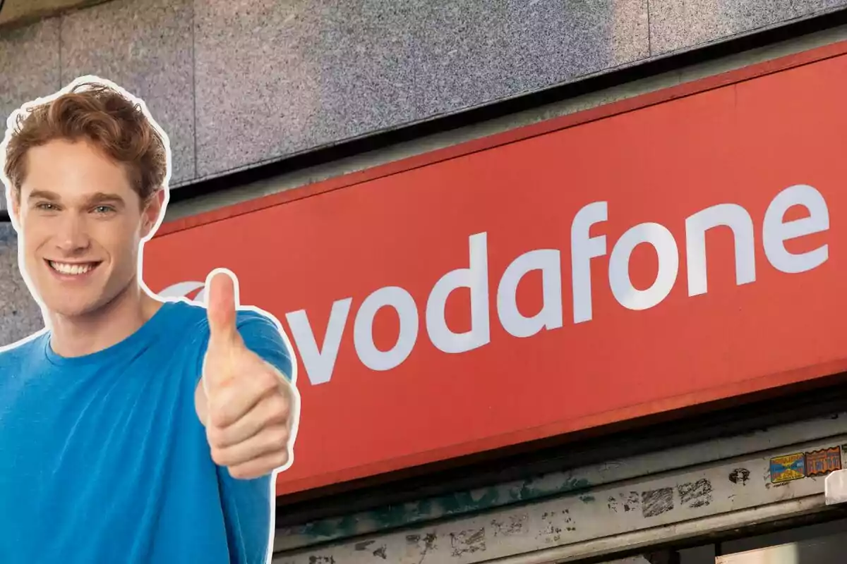 Hombre sonriendo con pulgar hacia arriba frente a un cartel de Vodafone.