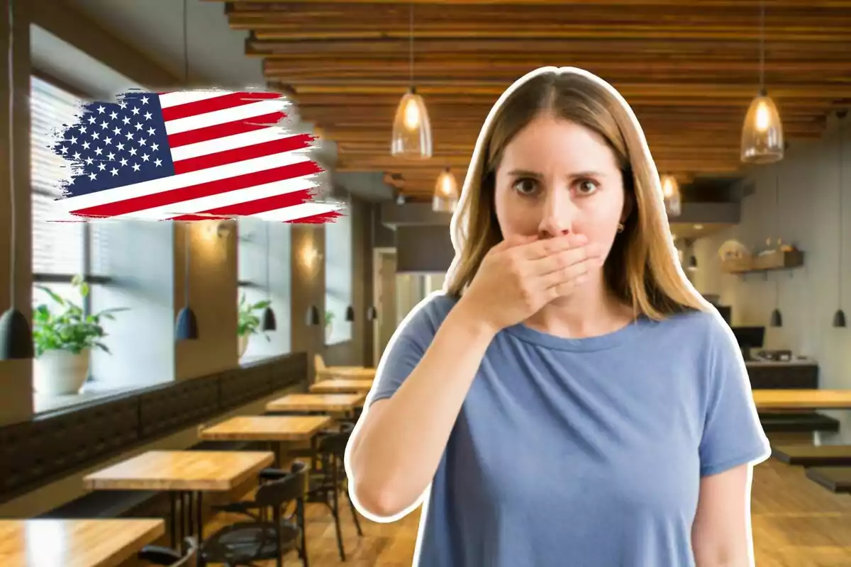 Mujer sorprendida cubriéndose la boca con una mano en un restaurante moderno con una bandera de Estados Unidos pintada al fondo