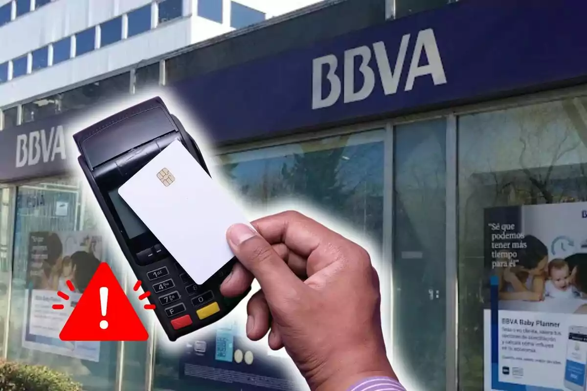 Una mano sosteniendo una tarjeta blanca frente a un lector de tarjetas con un edificio de BBVA de fondo y un icono de advertencia roja.