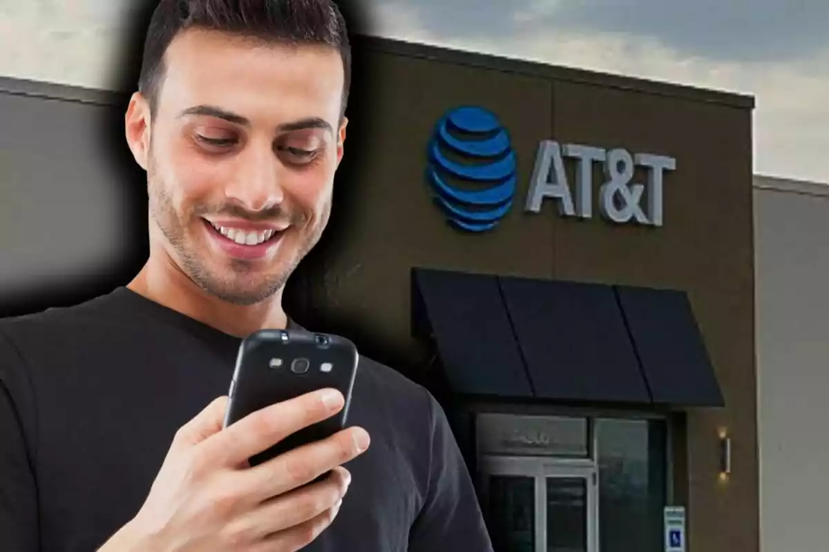 A smiling man looks at his phone in front of an AT&T store.