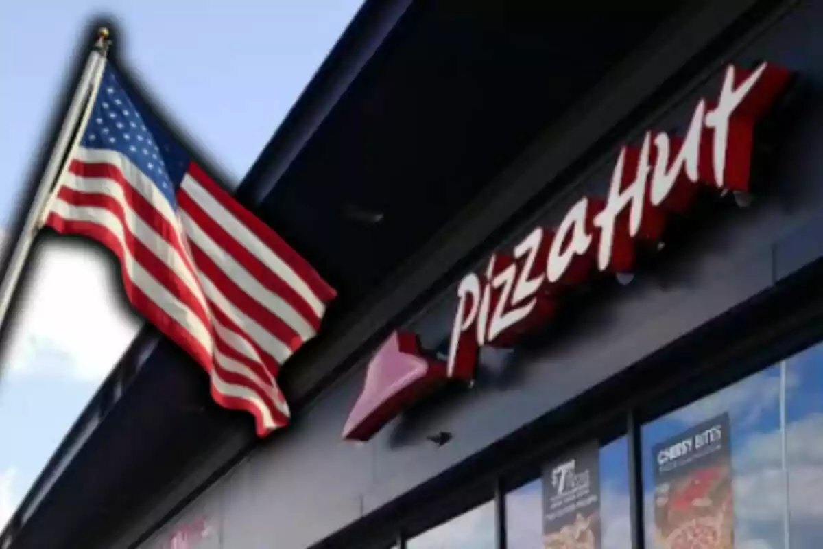 Facade of a Pizza Hut restaurant with a United States flag waving beside it. Facade of a Pizza Hut restaurant with a United States flag waving beside it.