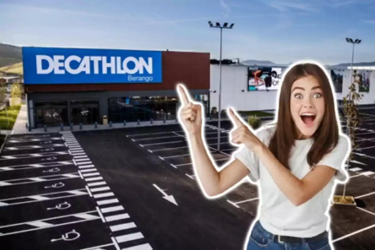 Una mujer sonriente señala hacia un edificio de Decathlon con un estacionamiento vacío en primer plano.