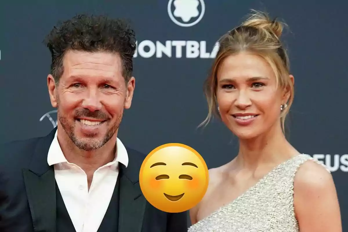 Diego Simeone and Carla Pereyra posing at a formal event with a smiling emoji covering part of the image