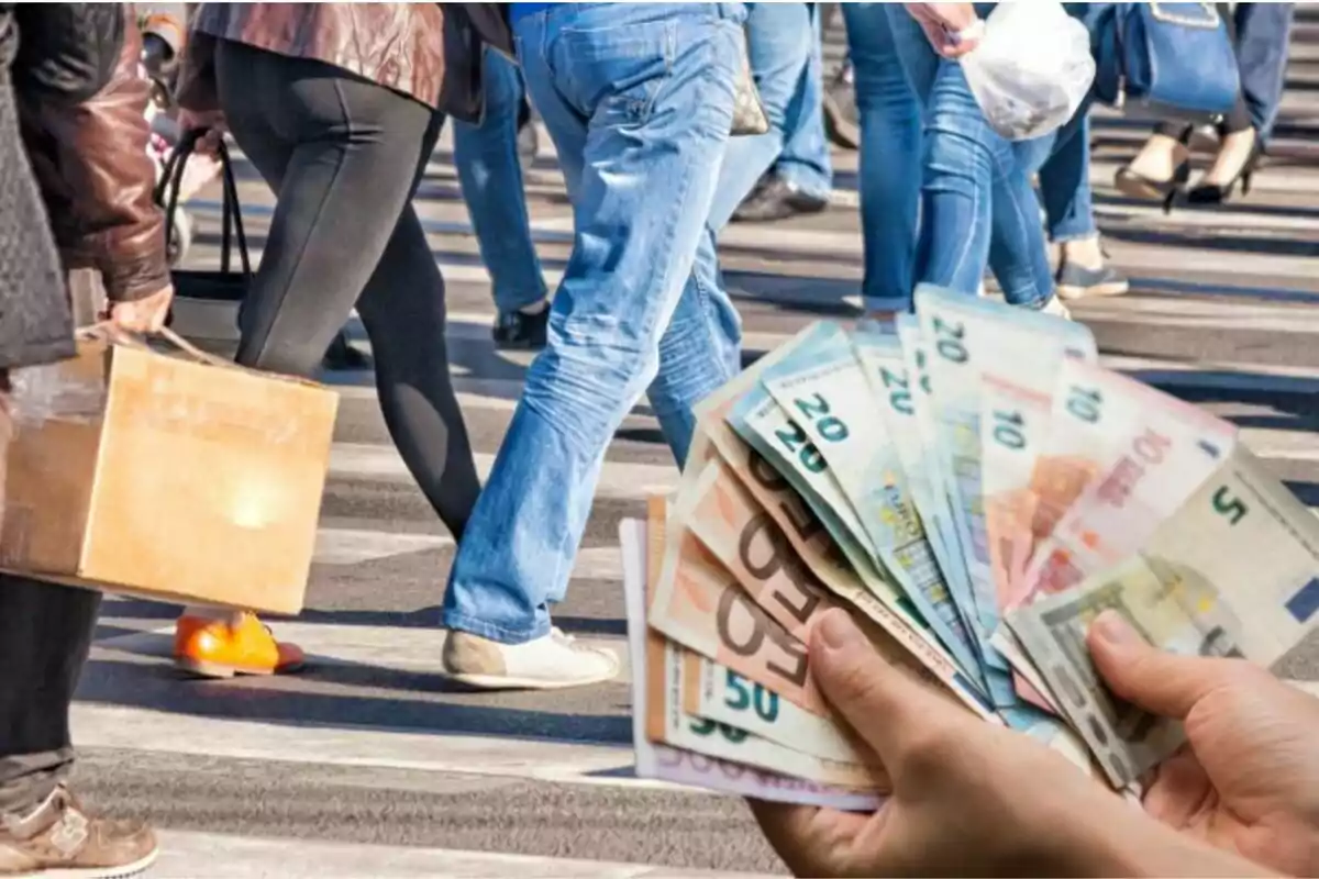 Personas caminando en la calle mientras alguien sostiene varios billetes en primer plano.