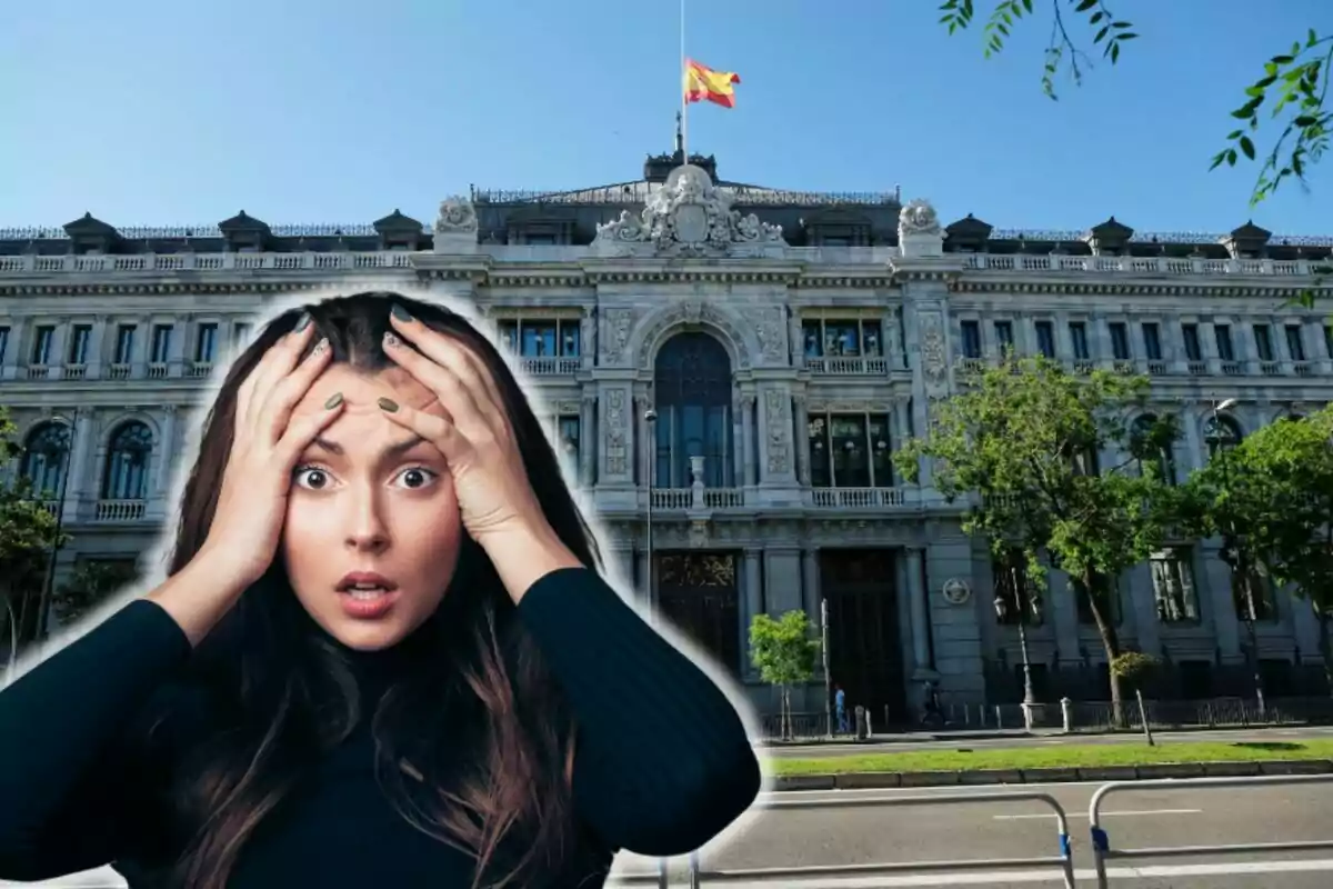 Una mujer con expresión de sorpresa o preocupación frente al Banco de España con una bandera de España ondeando en la parte superior.