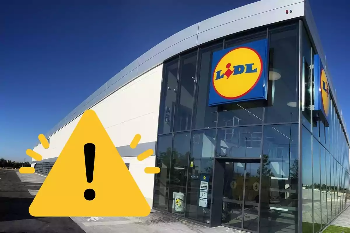 Fachada de una tienda Lidl con un símbolo de advertencia amarillo en primer plano.