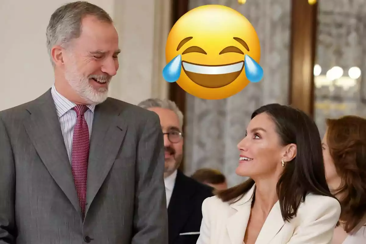 Felipe riendo en traje gris y corbata roja mirando a Letizia sonriendo en traje blanco y un emoji riendo