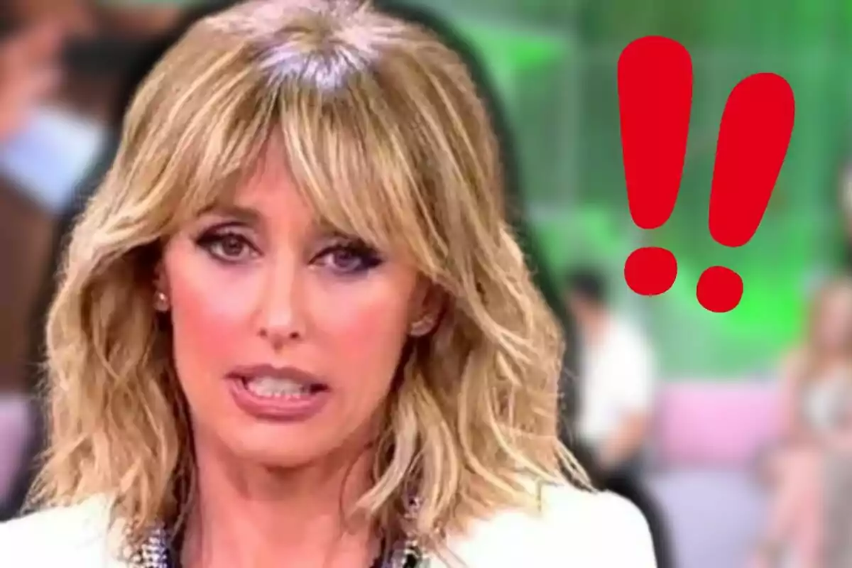 Emma García con expresión de sorpresa o preocupación en un set de televisión con dos signos de exclamación rojos al fondo