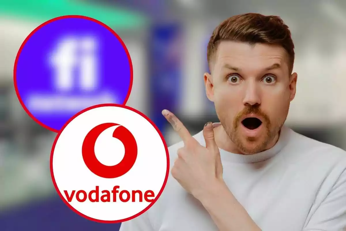 Un hombre sorprendido señala hacia los logotipos de dos compañías de telecomunicaciones, uno de Vodafone y otro borroso.