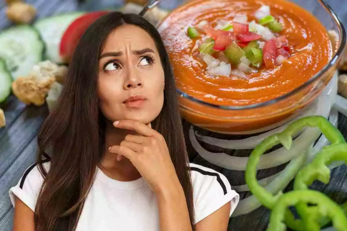 Mujer pensativa frente a un plato de sopa de tomate con verduras picadas.