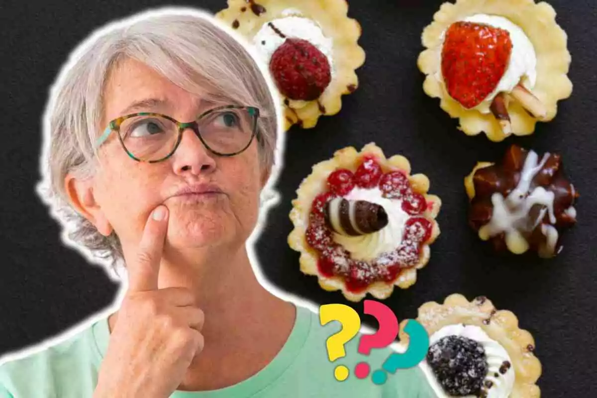 Una persona mayor con gafas parece estar pensando mientras observa una selección de pequeños pasteles decorados con frutas y crema, con signos de interrogación de colores en la parte inferior.