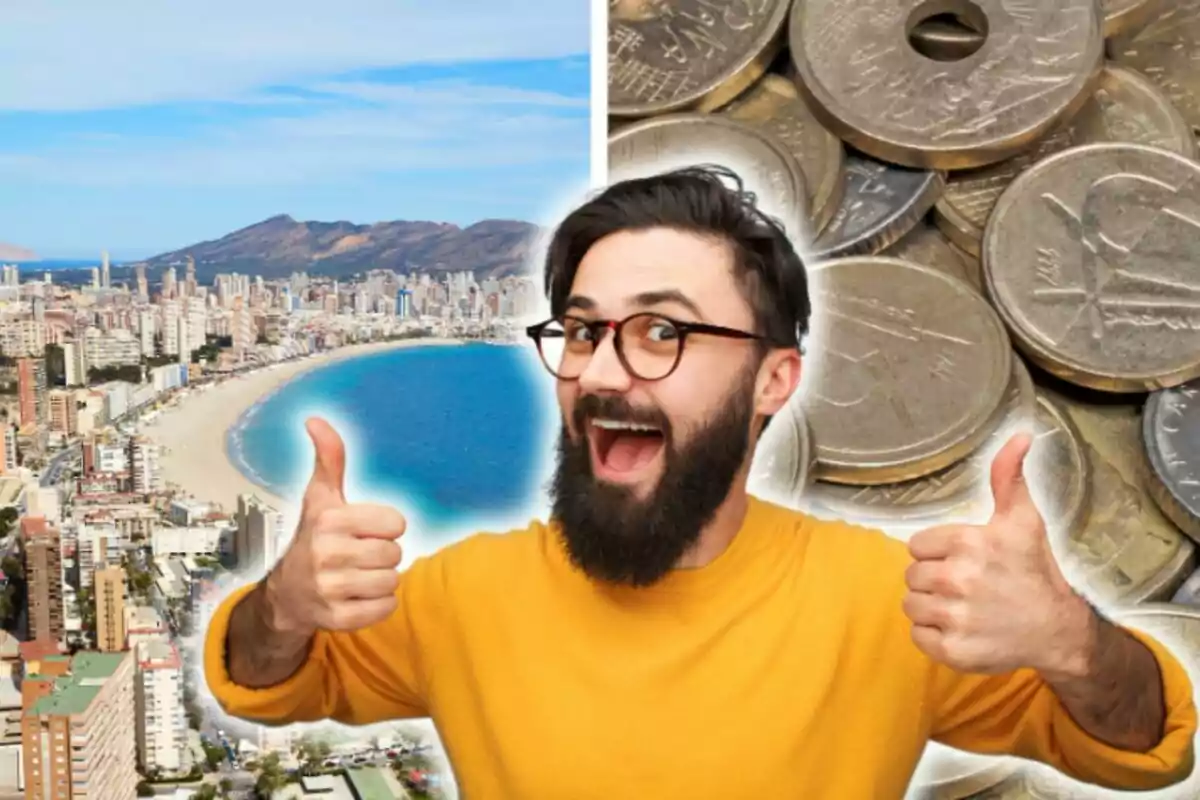 Un hombre con gafas y barba sonríe y muestra ambos pulgares hacia arriba, con una playa y una pila de monedas en el fondo.