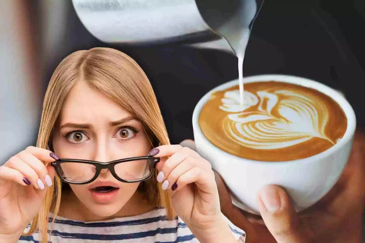 Una mujer con expresión de sorpresa sostiene sus gafas mientras observa una taza de café con arte latte.