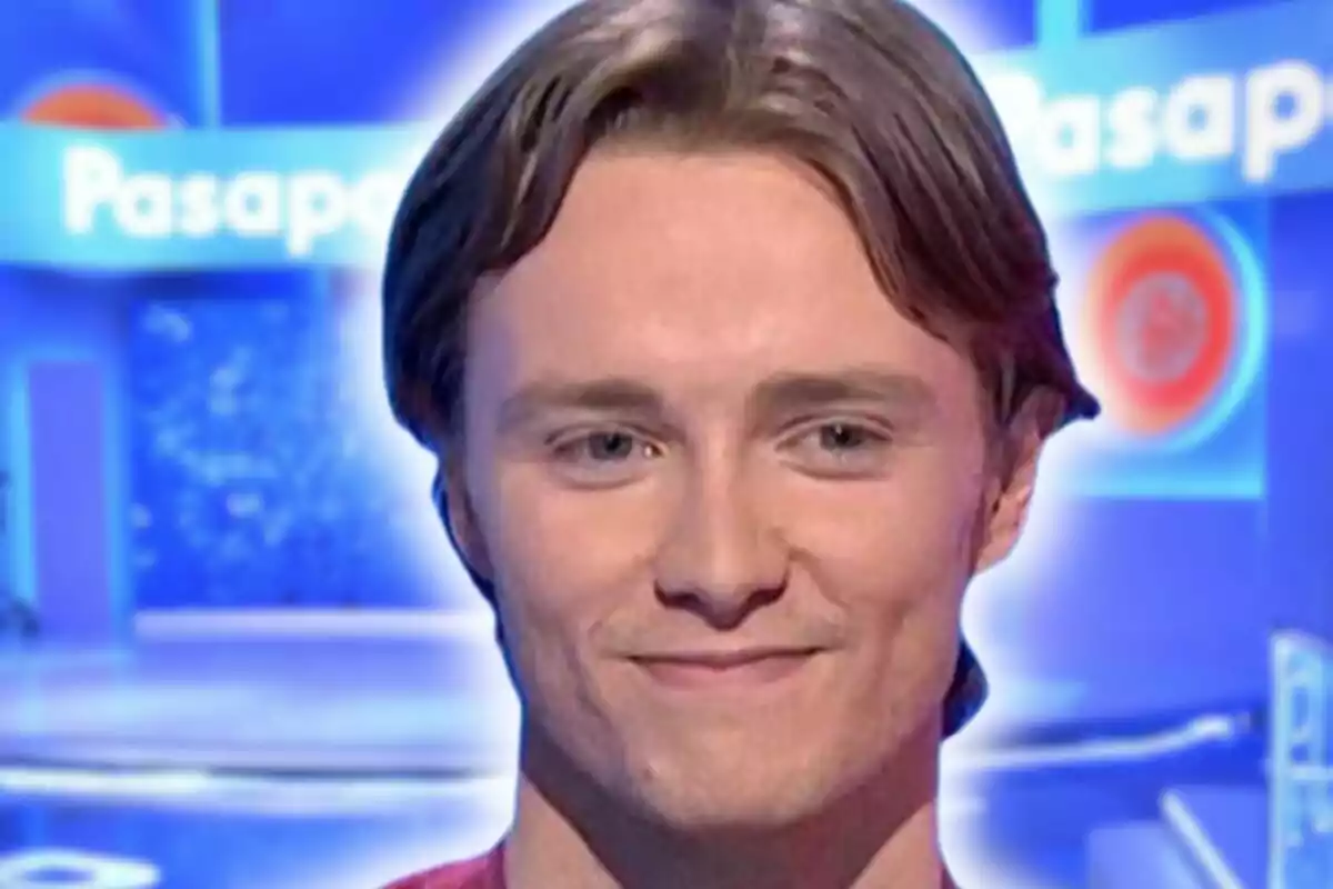 Photo montage of Manu Pascual slightly smiling in front of a blue background with the logo of a TV show called 'Pasapalabra'.