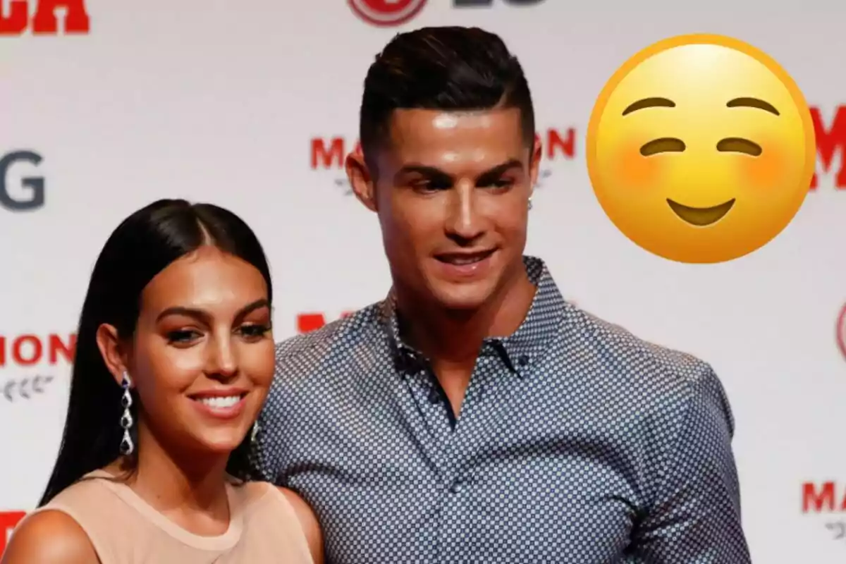 Georgina Rodríguez y Cristiano Ronaldo posando sonriente en un evento con un emoji de cara sonriente al fondo