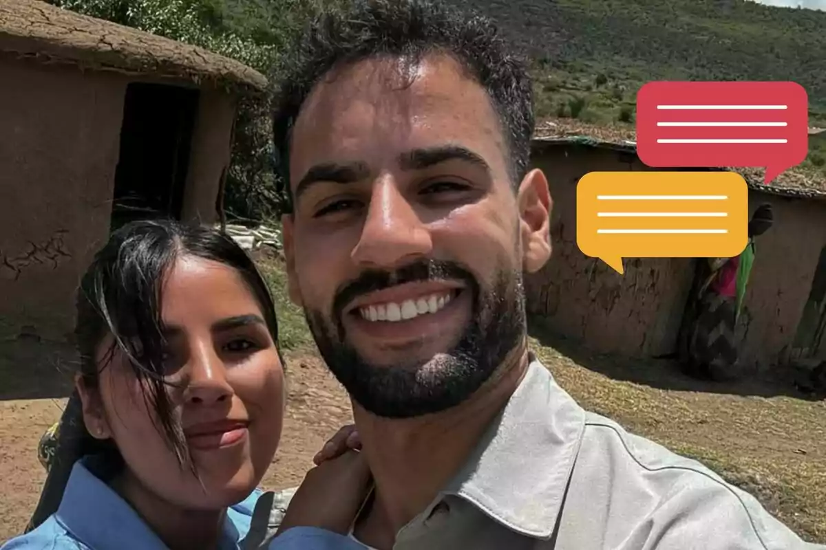 Isa Pantoja y Asraf Beno sonríe mientras se toma una selfie al aire libre frente a casas de adobe, con burbujas de diálogo de colores editadas en la imagen.