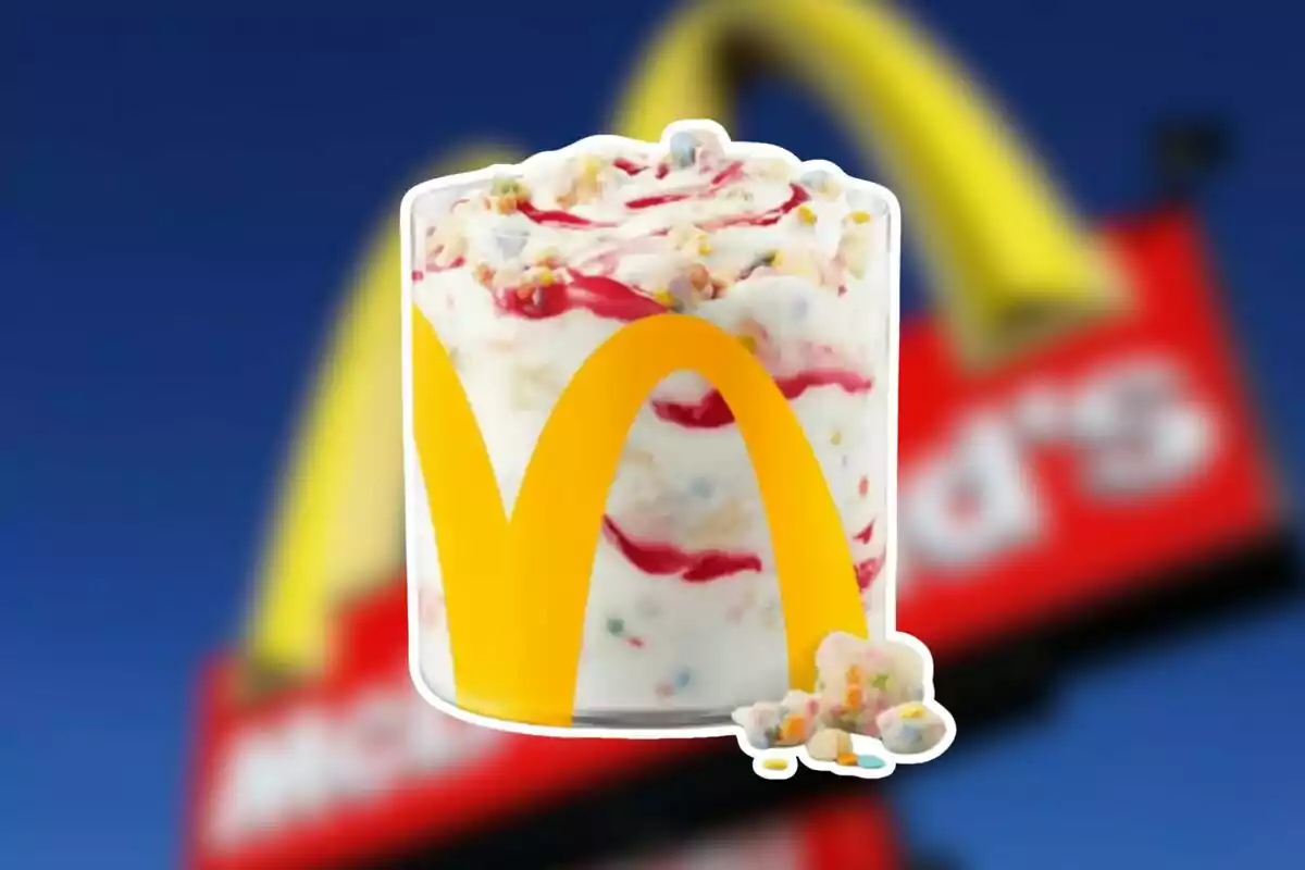 Un vaso de helado con topping de colores y logo amarillo sobre un fondo desenfocado de un letrero rojo y azul. Un vaso de helado con topping de colores y logo amarillo sobre un fondo desenfocado de un letrero rojo y azul.