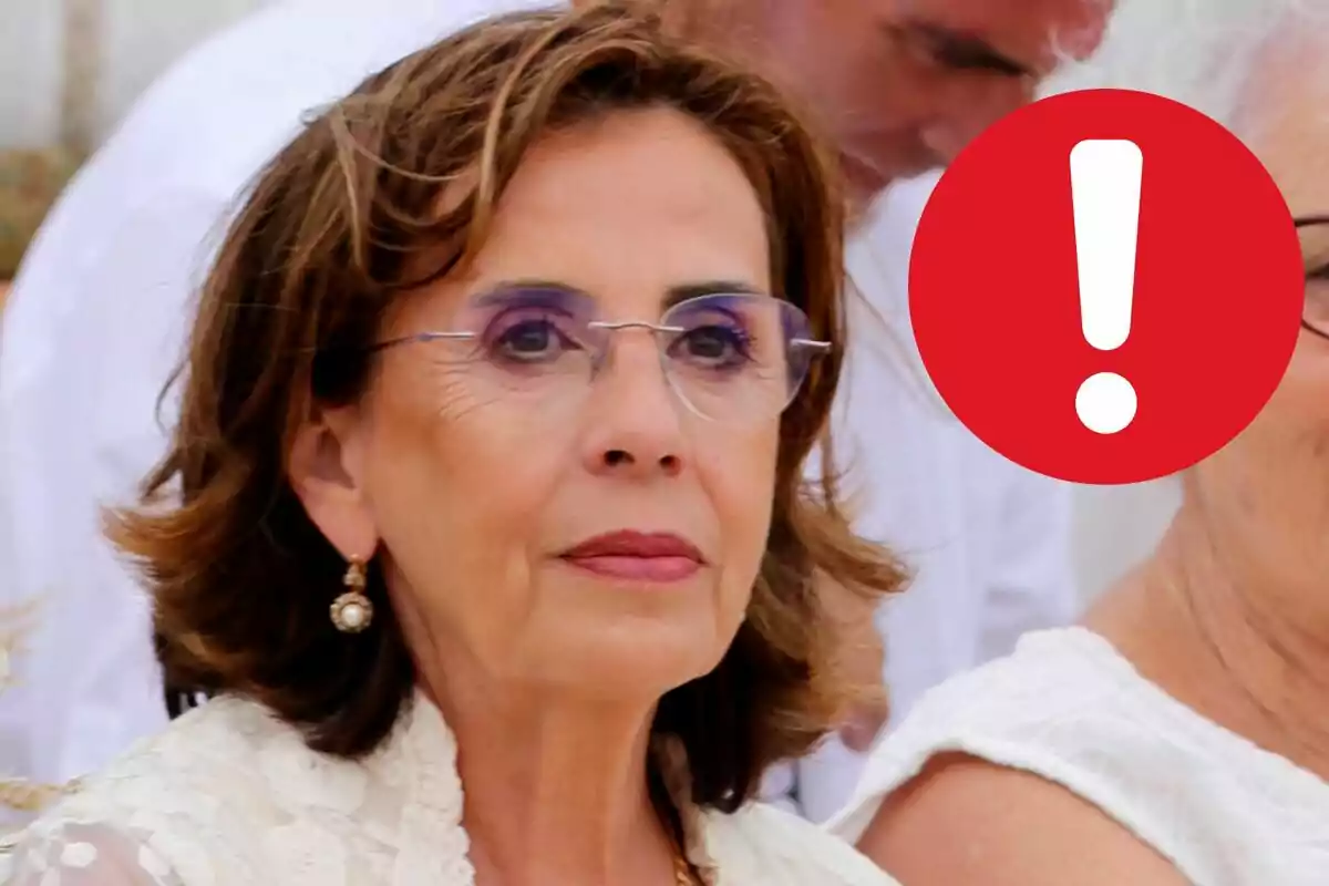 Mercedes Bernal with glasses and a serious expression, with a red warning icon in the corner.