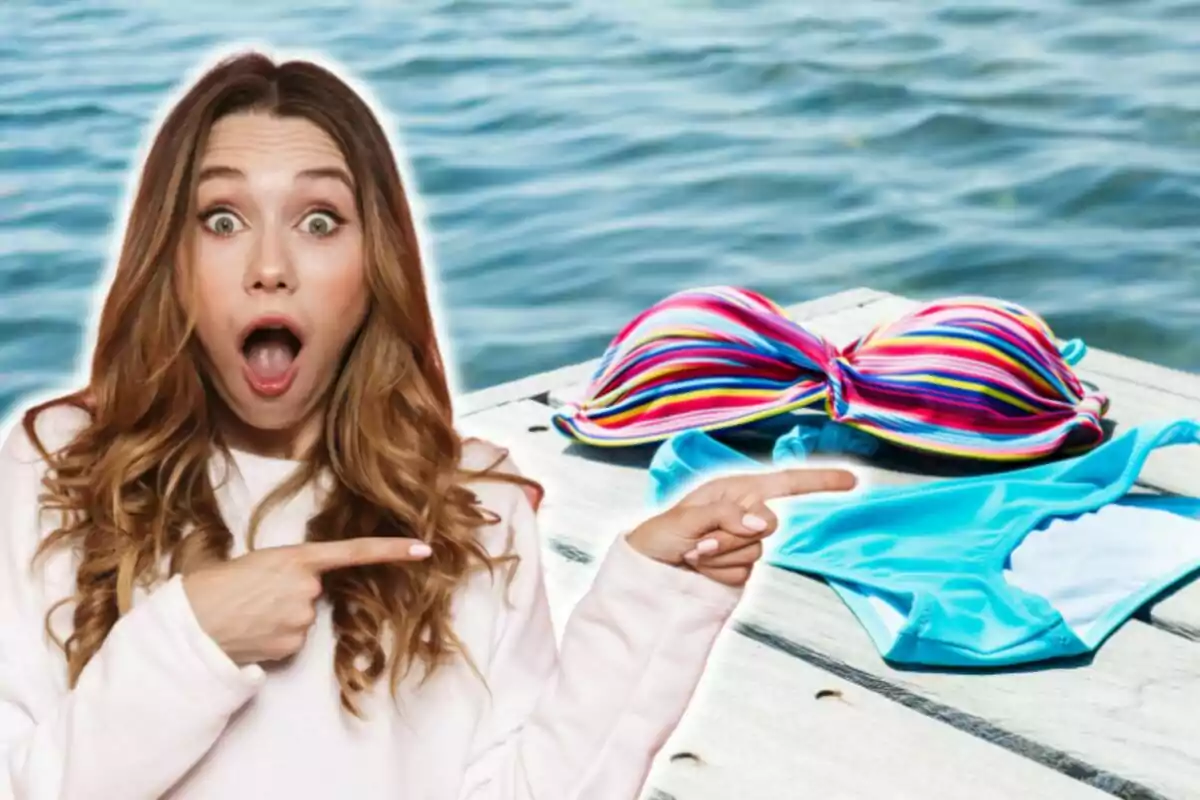 Mujer sorprendida señalando un bikini de colores sobre un muelle junto al agua.