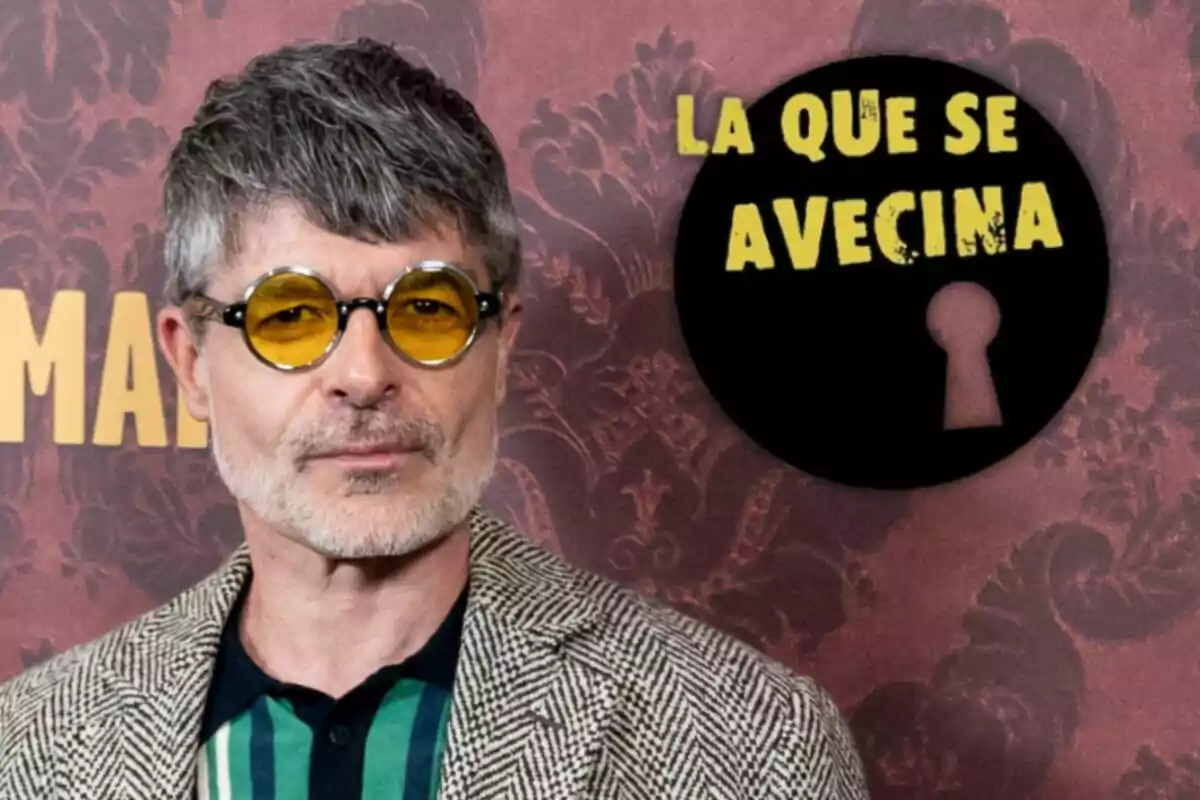 Nacho Guerreros con gafas de sol amarillas y cabello canoso frente a un fondo con el logo de "La que se avecina".