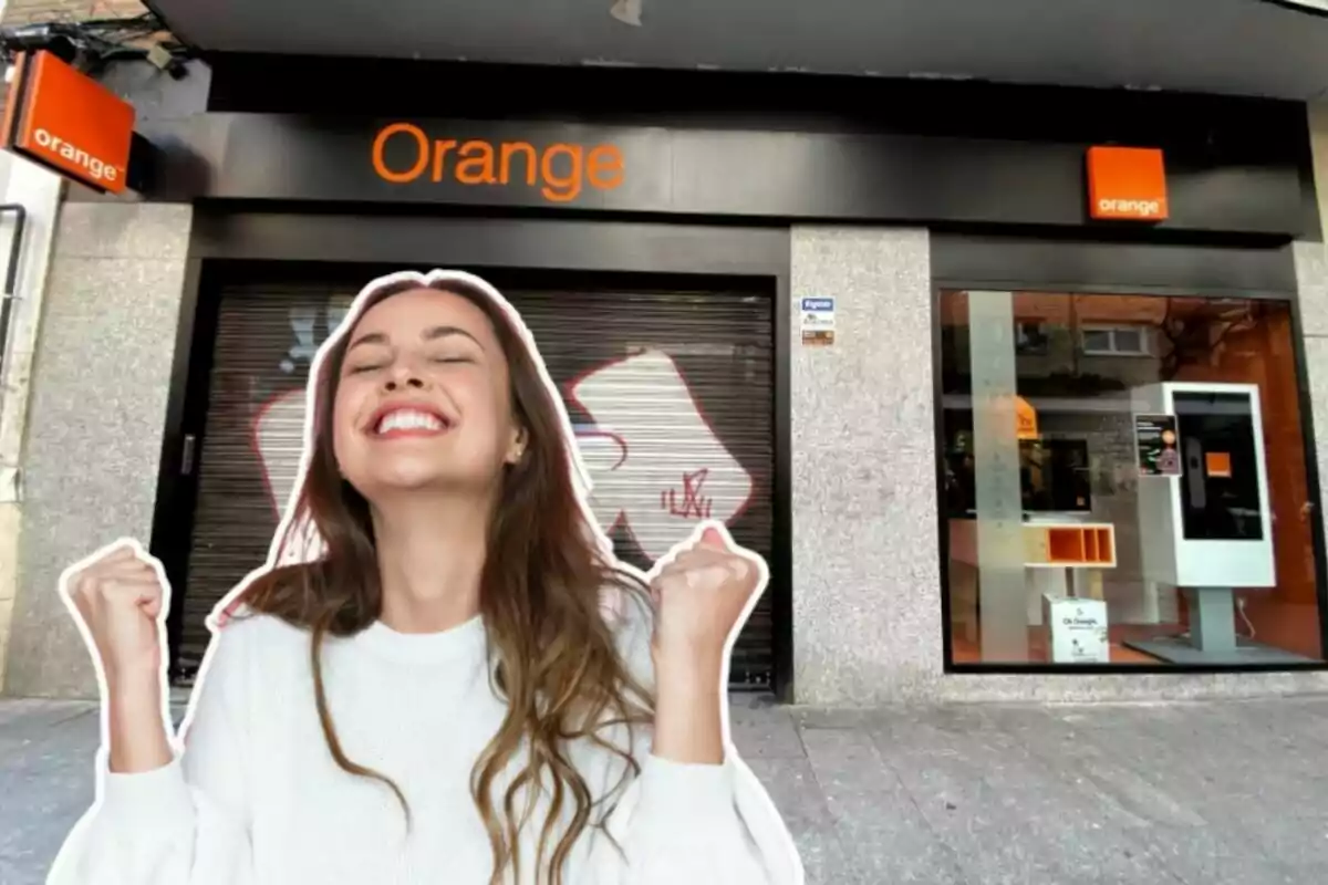 Una tienda de Orange al fondo, y en primer plano una chica con los brazos en alto y gesto de felicidad