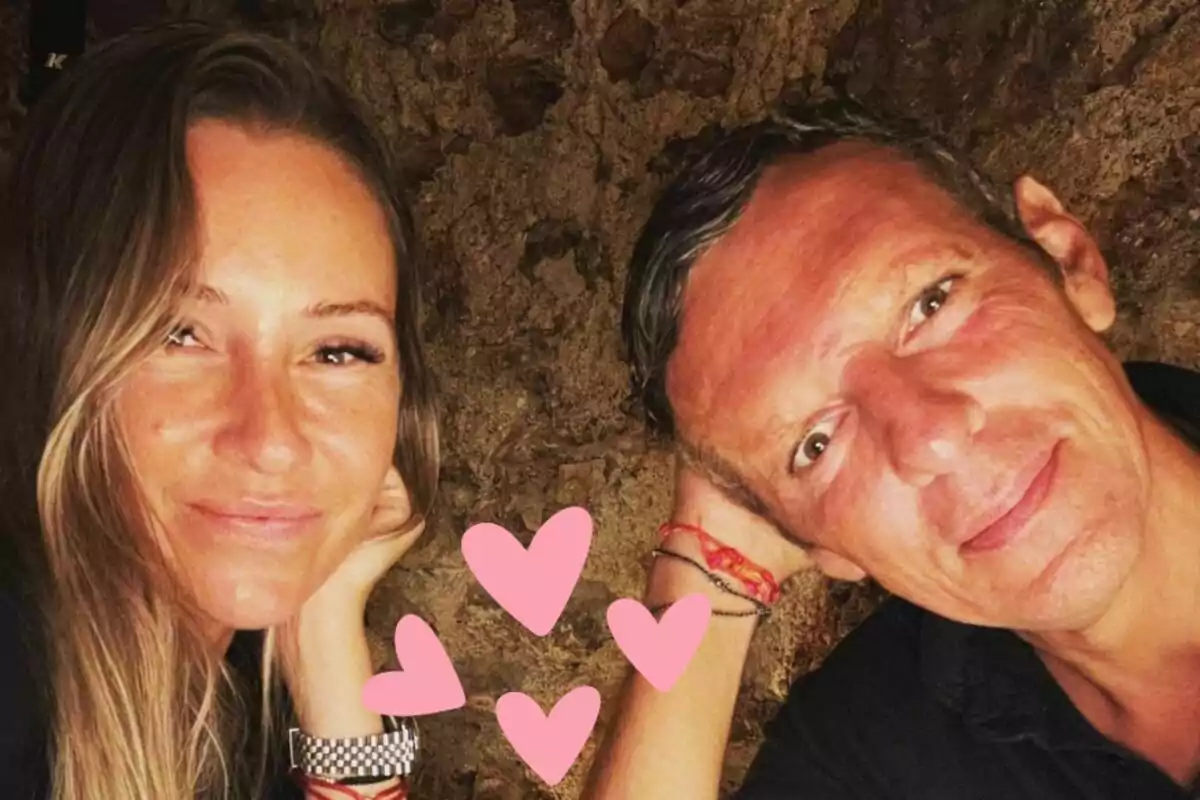 Alexia Pla y Joaquín Prat sonrientes posan para una foto con corazones rosados superpuestos en la parte inferior.