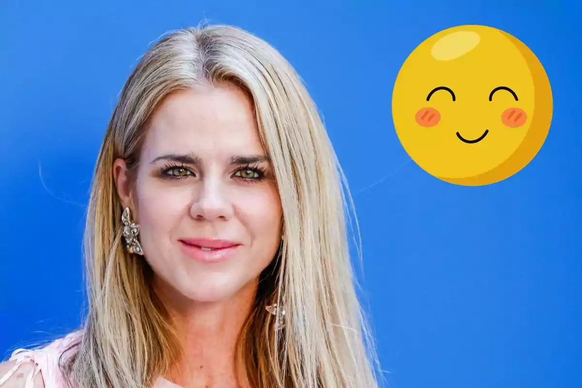 Amelia Bono rubia con aretes grandes frente a un fondo azul junto a un emoji sonriente.