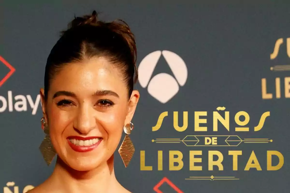 Candela Cruz sonriente con pendientes grandes frente a un cartel que dice "Sueños de Libertad".