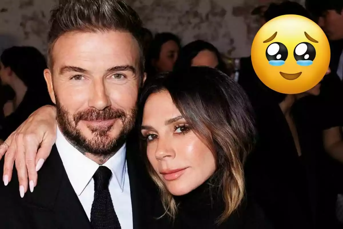 David y Victoria Beckham posando juntos en un evento con un emoji de ojos llorosos en la esquina superior derecha.