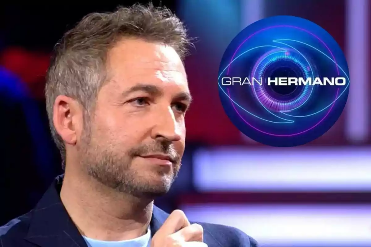 Fran Blanco con barba y cabello corto en un estudio de televisión con el logo de Gran Hermano en el fondo.