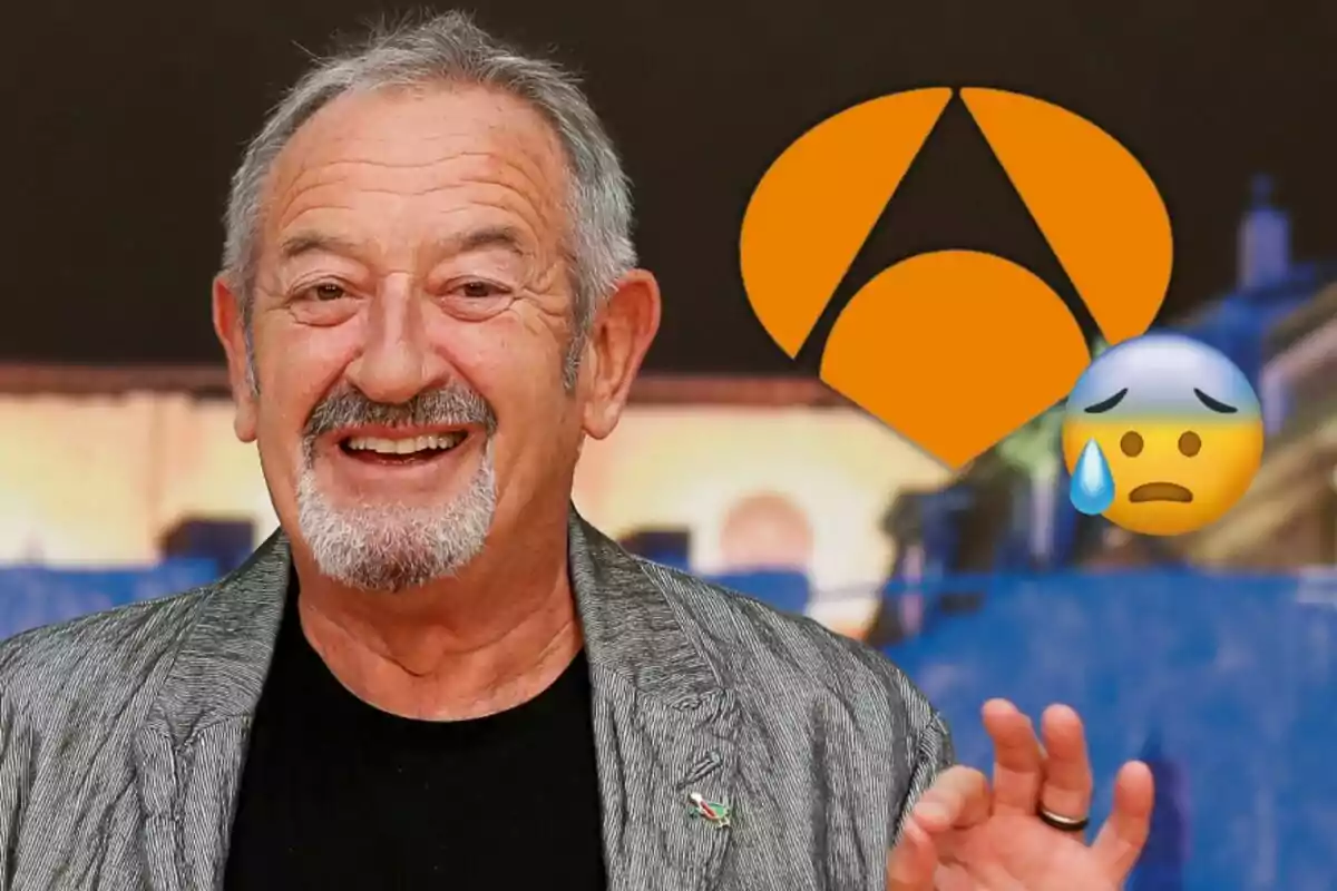 Karlos Arguiñano sonriente con barba y cabello canoso, vistiendo una chaqueta gris, con un logotipo naranja y un emoji de cara preocupada al fondo.