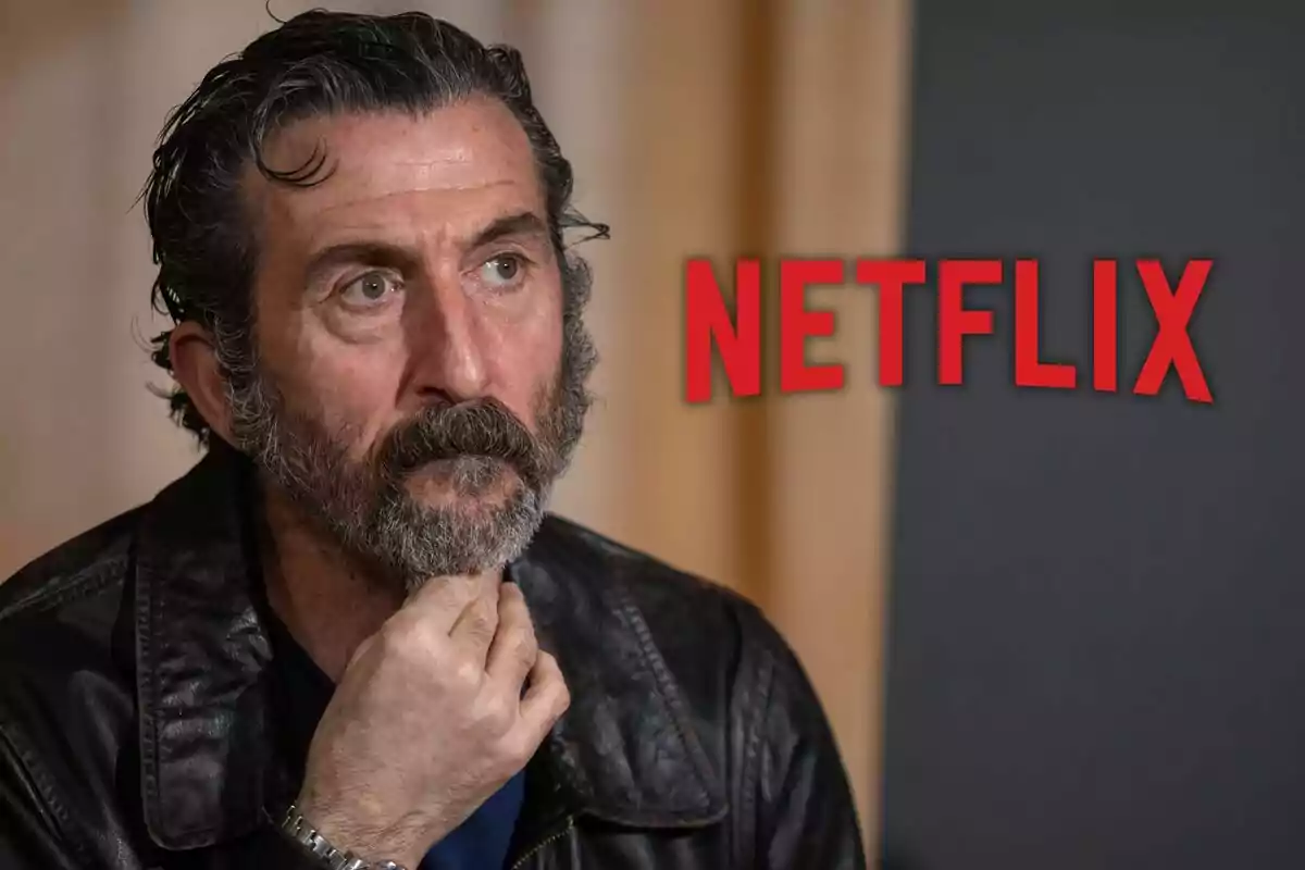 Luis Zahera con chaqueta de cuero y barba pensativa con el logo de Netflix al fondo.