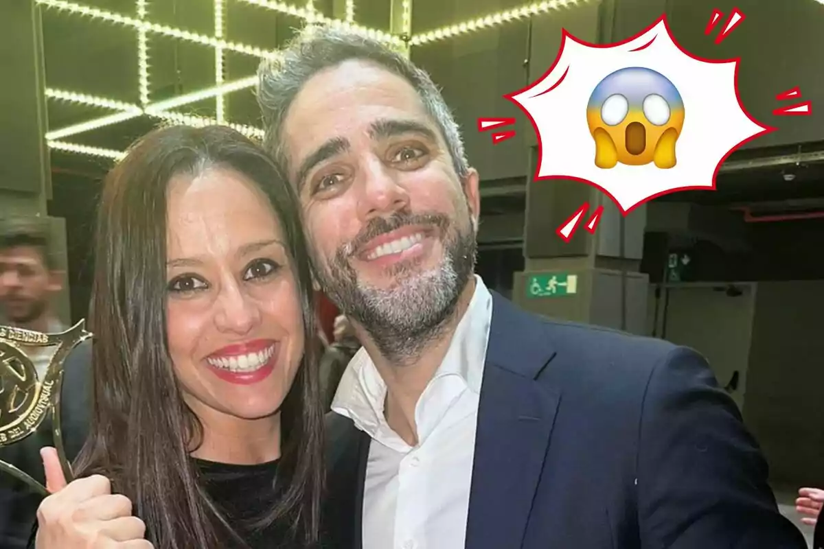 Sara Rubio y Roberto Leal sonríen mientras ella sostiene un trofeo, con un emoji sorprendido en la esquina superior derecha.