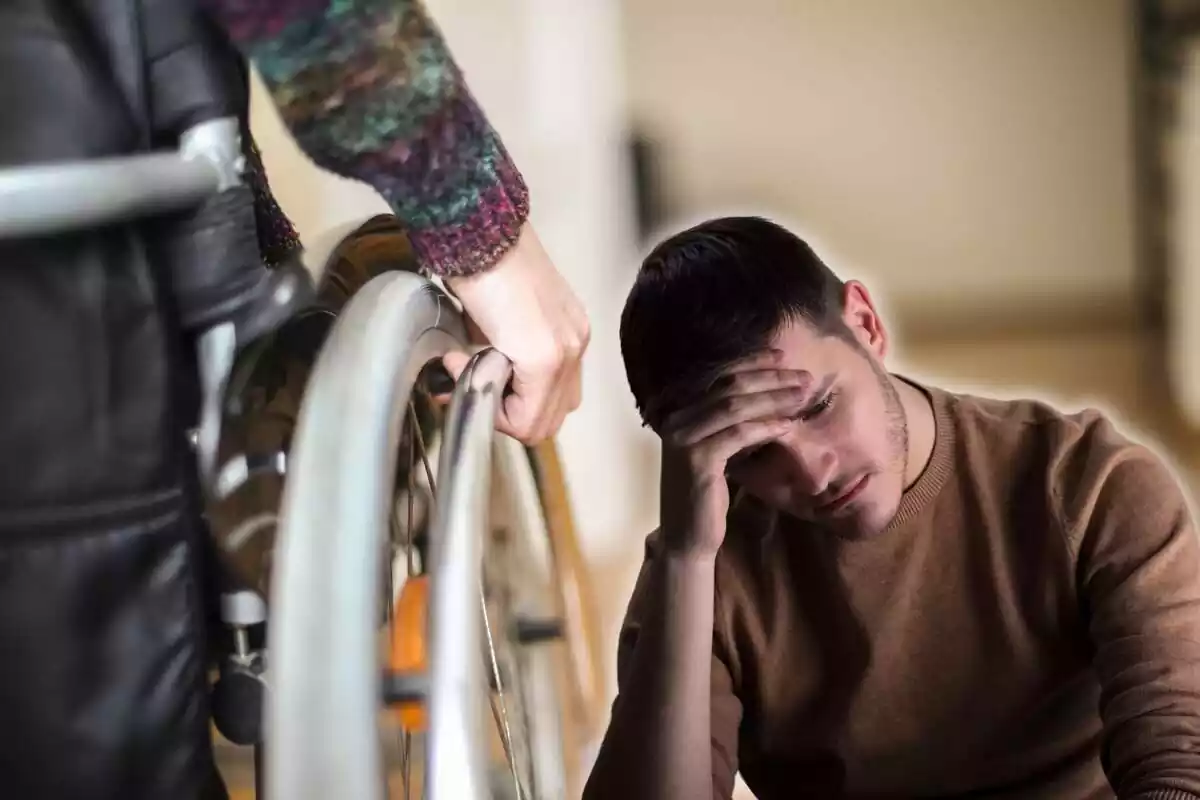 Un hombre en silla de ruedas, de espaldas, y otro se lamenta, con la mano en la frente Un hombre en silla de ruedas, de espaldas, y otro se lamenta, con la mano en la frente