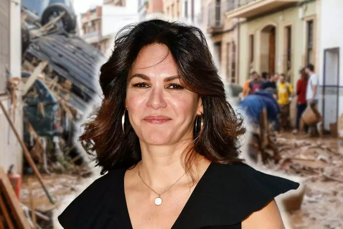 Fabiola Martínez sonriente con cabello oscuro y vestido negro está en primer plano mientras que al fondo se observa una calle con escombros y personas trabajando.