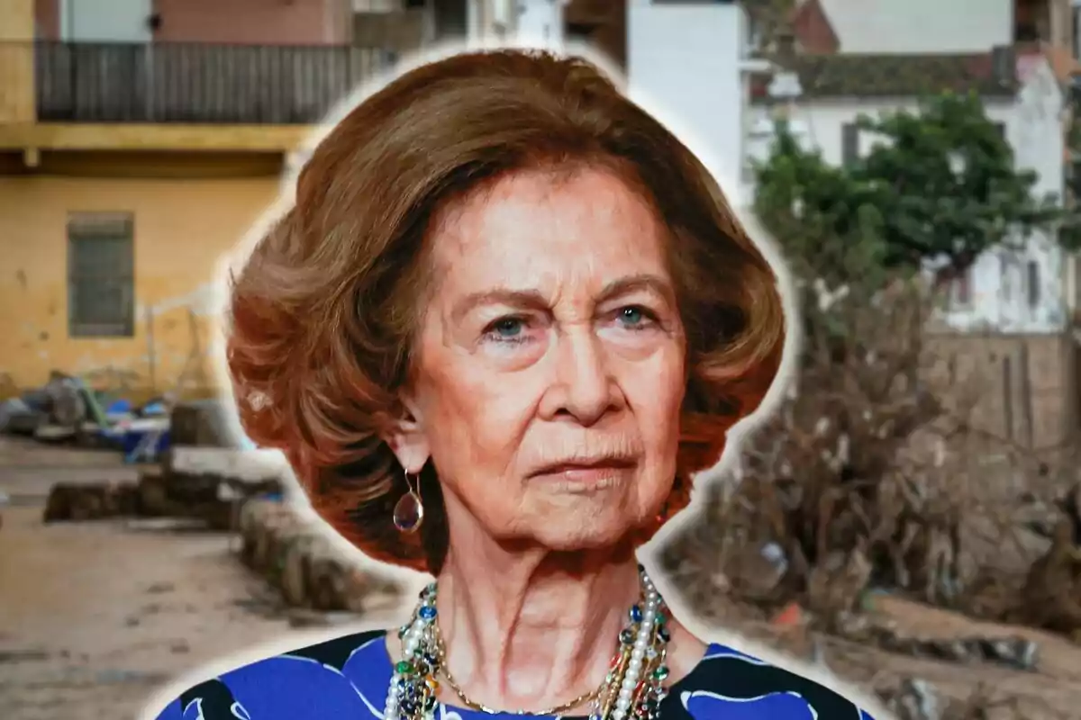 Queen Sofia with brown hair and a serious expression wears a pearl necklace and earrings in an urban setting.