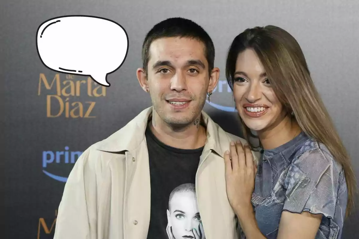 Víctor Elías y Ana Guerra sonriente posando en un evento con un globo de diálogo vacío sobre el hombre.