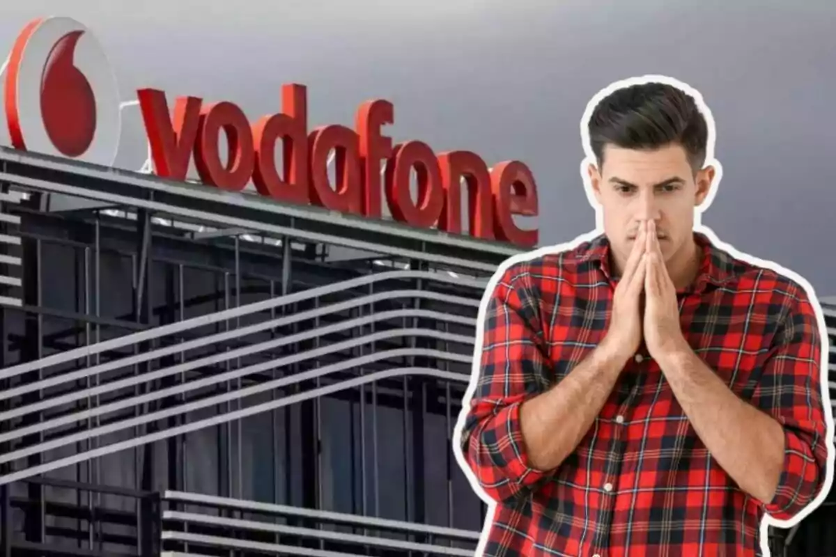 A man in a checked jersey looks worried in front of a building with the Vodafone logo.