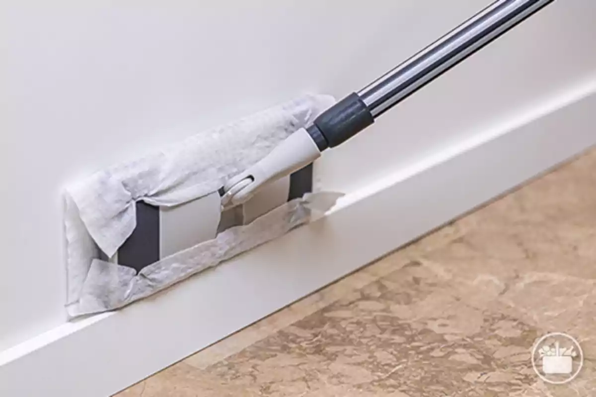 Una mopa limpiando un zócalo blanco sobre un suelo de mármol. Una mopa limpiando un zócalo blanco sobre un suelo de mármol.