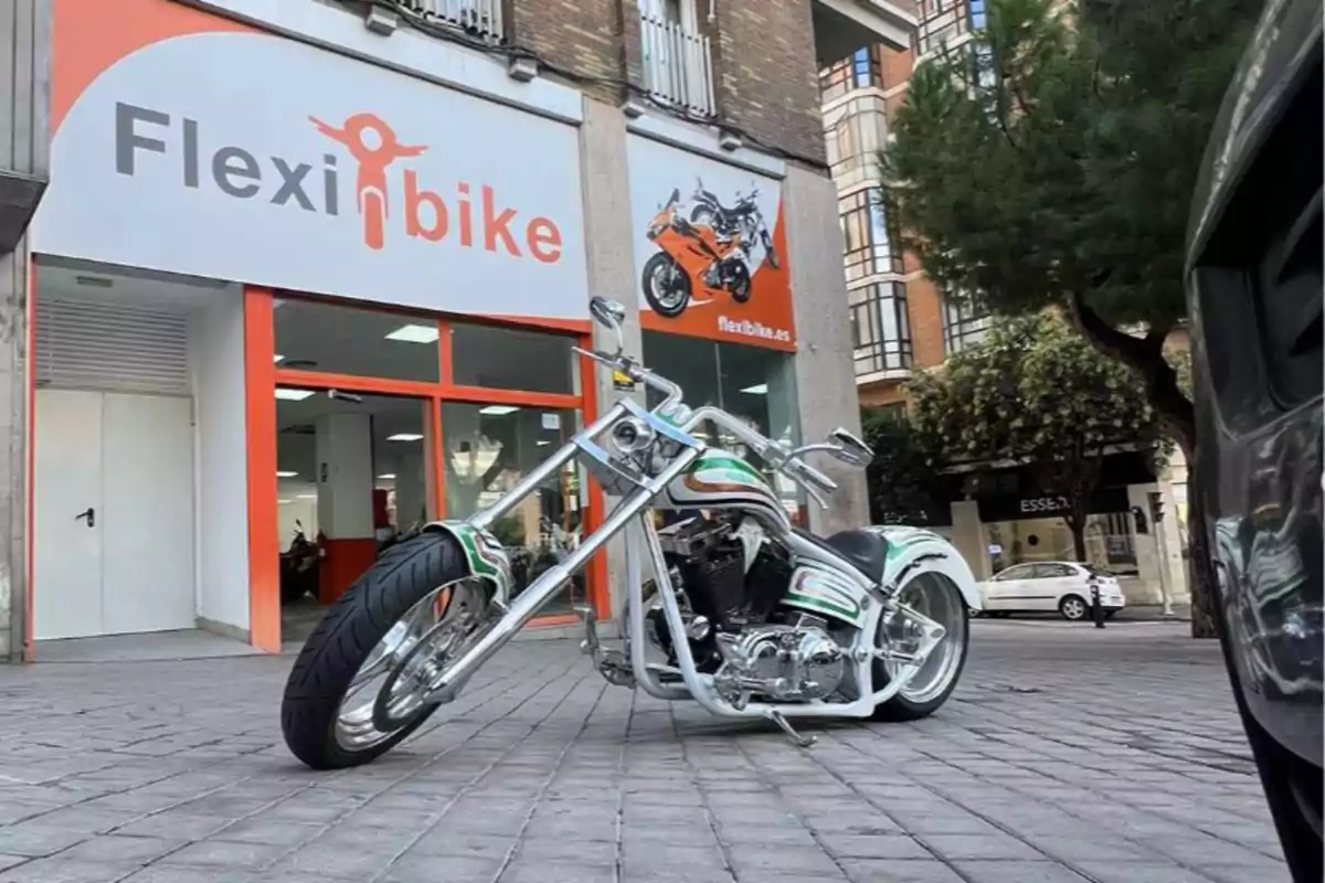 Motocicleta tipo chopper estacionada frente a una tienda de motos llamada Flexibike en una zona urbana