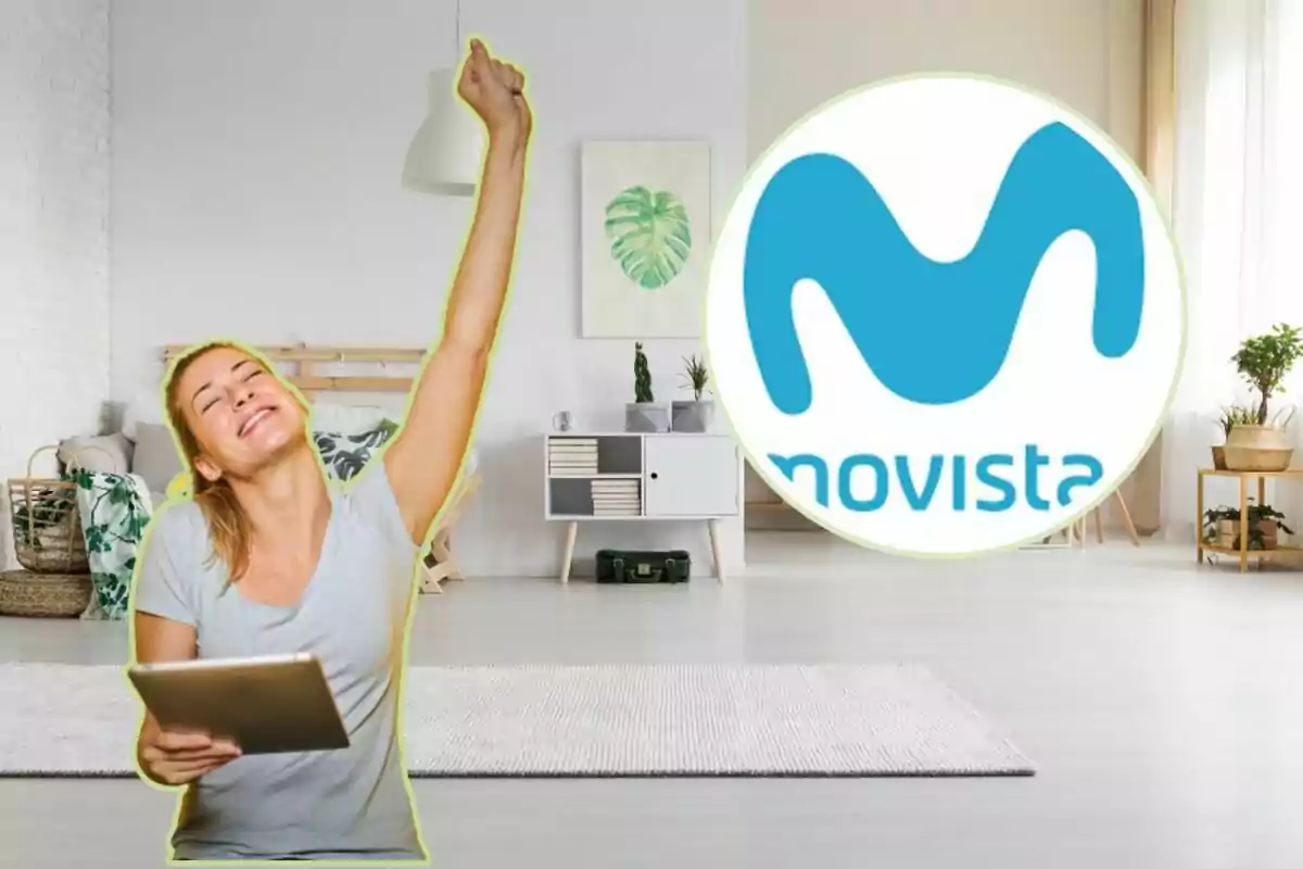 Mujer feliz levantando el brazo con una tableta en la mano, con el logo de Movistar en el fondo de una sala moderna.