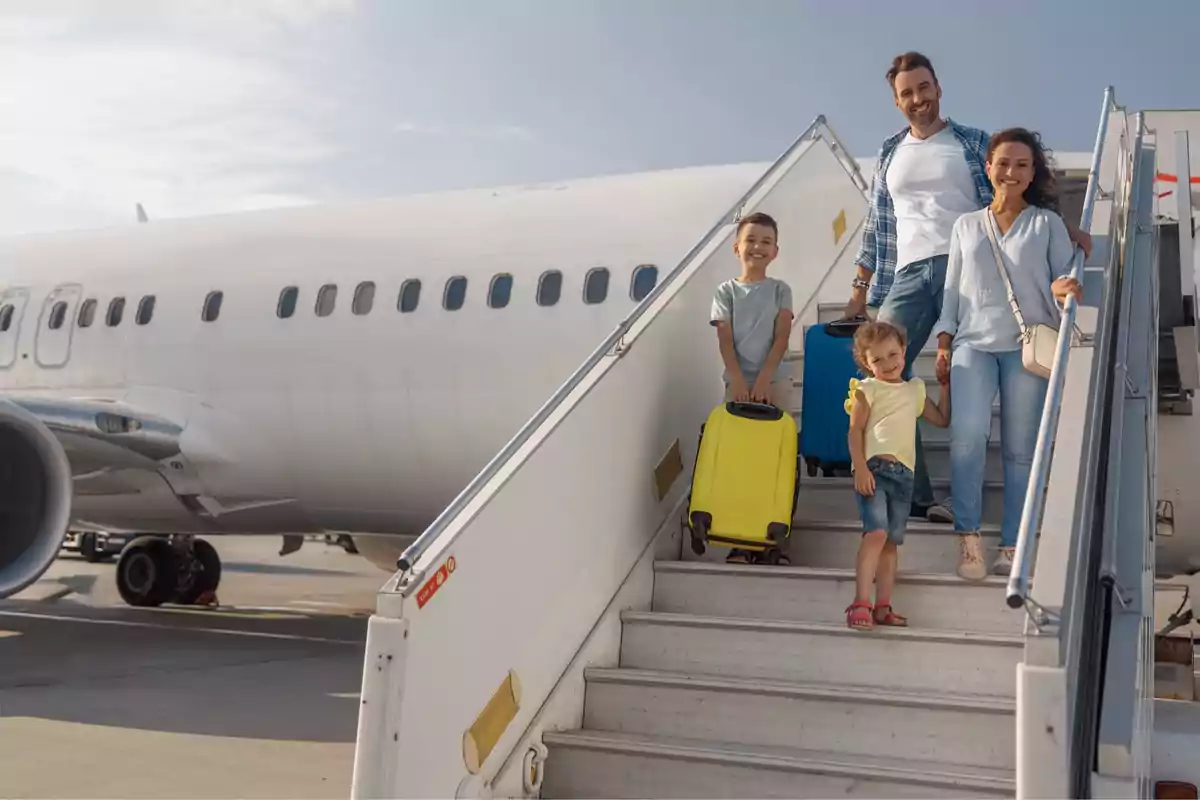 Family getting off a plane with suitcases on a sunny day.