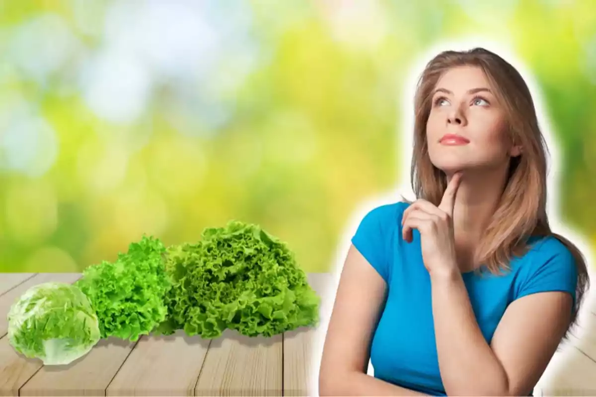 Una mujer pensativa con una camiseta azul junto a varias lechugas sobre una mesa de madera, con un fondo desenfocado de colores verdes y amarillos.