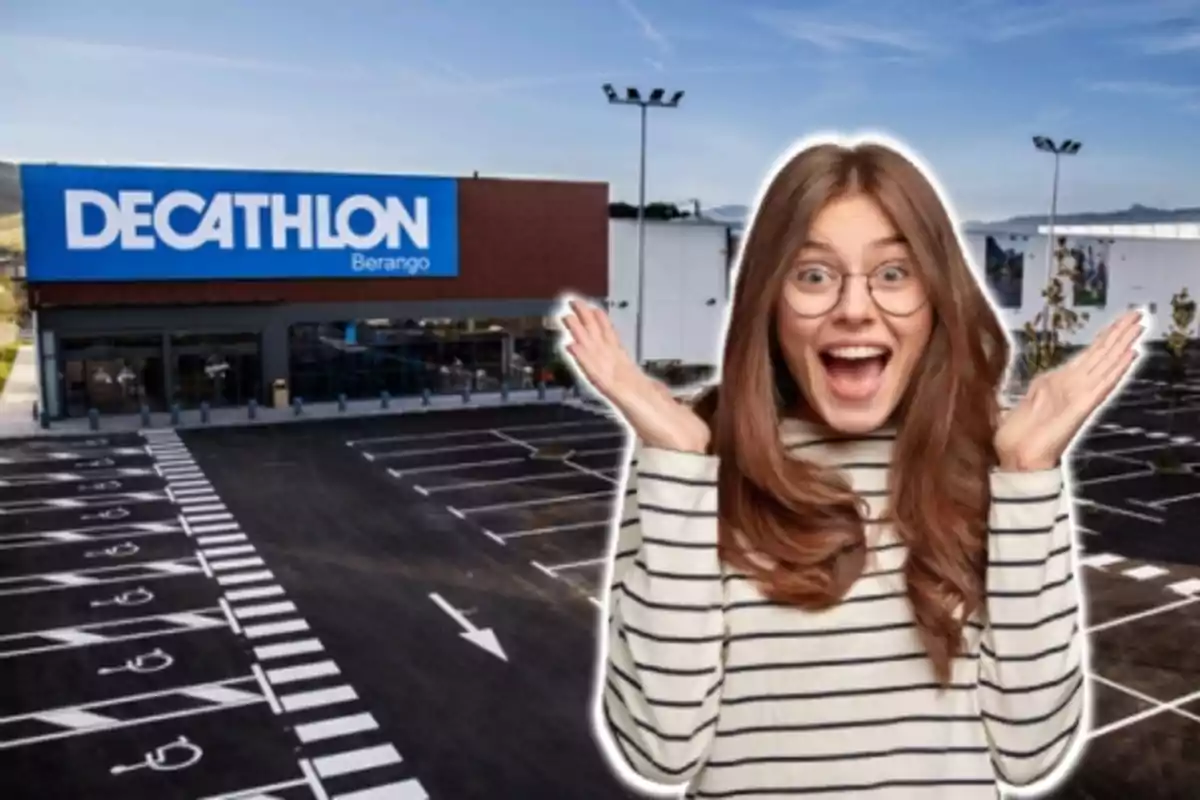 Una mujer sonriente con gafas y suéter a rayas está frente a una tienda Decathlon con un estacionamiento vacío.