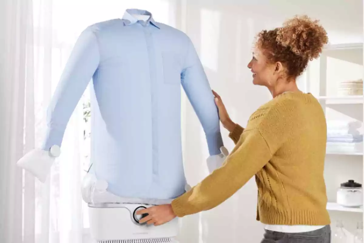 Mujer usando un maniquí inflable para secar y planchar una camisa azul en una habitación iluminada Mujer usando un maniquí inflable para secar y planchar una camisa azul en una habitación iluminada