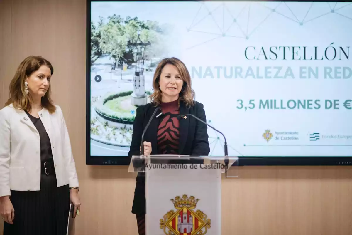 Two women at a press conference in Castellón City Hall with a sign behind them that mentions "Castellón Nature Network" and "3.5 million €".