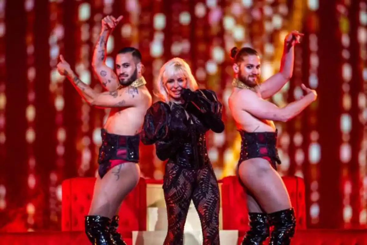 La cantante Nebulossa sobre un escenario cantando la canción Zorra, acompañada por sus dos bailarines que llevan atuendo femenino