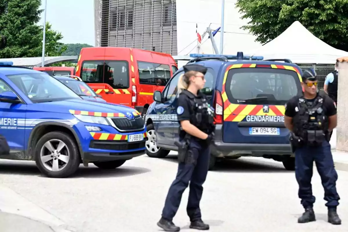 Policías fuertemente armados custodian una zona acordonada con vehículos oficiales de la gendarmería y servicios de emergencia en el fondo Policías fuertemente armados custodian una zona acordonada con vehículos oficiales de la gendarmería y servicios de emergencia en el fondo