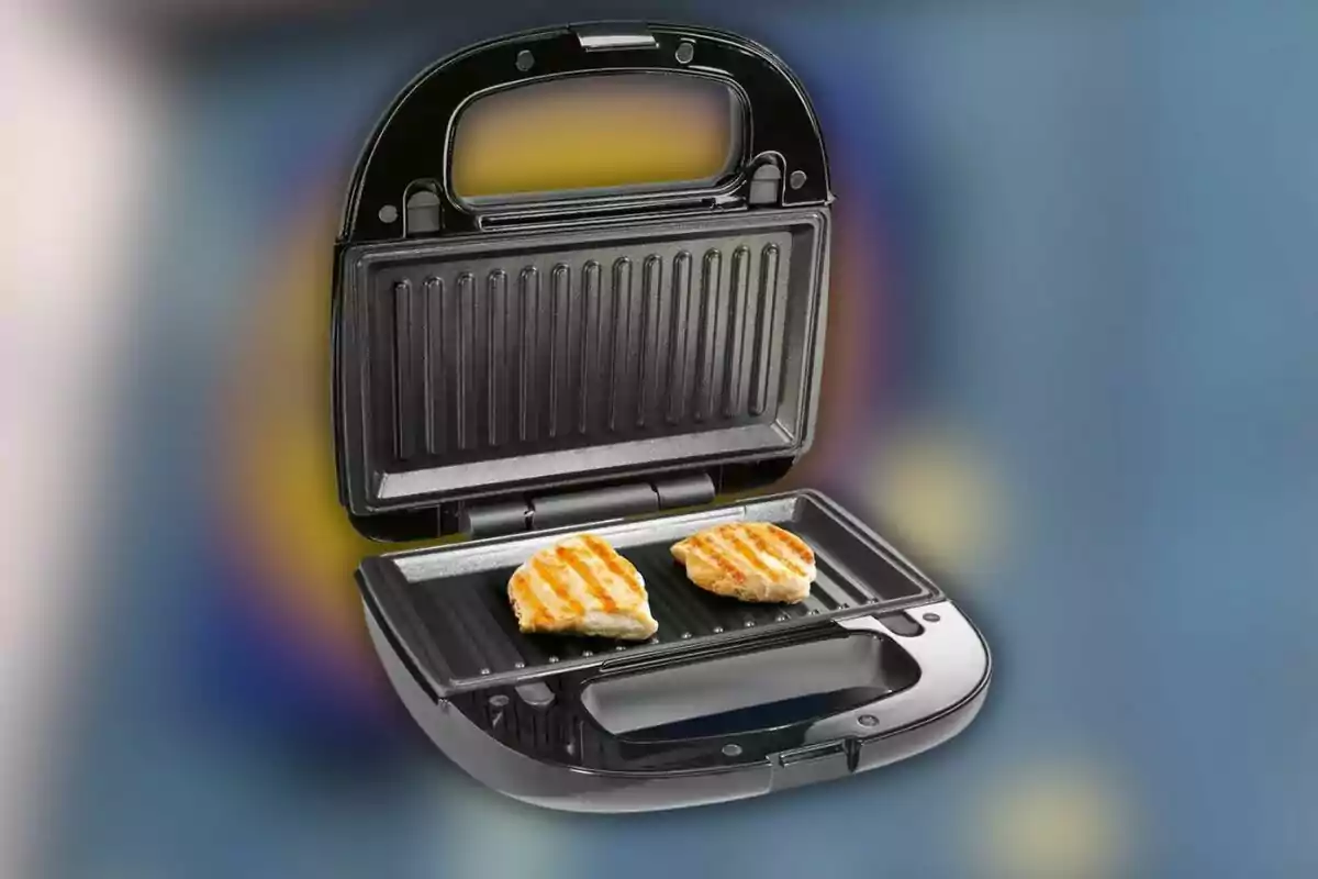 Una sandwichera abierta con dos piezas de pollo asado en su interior sobre un fondo desenfocado. Una sandwichera abierta con dos piezas de pollo asado en su interior sobre un fondo desenfocado.